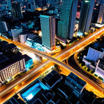 **Prompt 1:** Aerial view of a bustling Bangkok at night, seen from a high altitude, showcasing a complex tapestry of urban lights. Bright, concentrated clusters delineate business districts like Sathorn and Asoke, with subtle variations in brightness hinting at daily human activity shifts between weekdays and weekends. Expanding lines of light extend outwards, indicating recent urban growth and infrastructure development, like new BTS lines. The image should convey the city as a living, breathing network of illuminated data, vibrant and full of intricate details, emphasizing economic activity and population movement.
